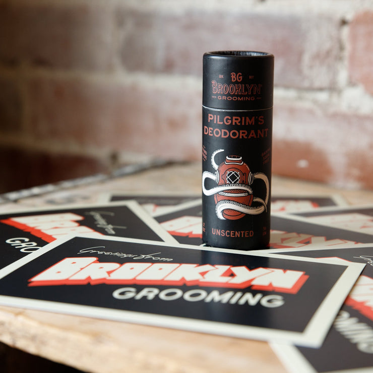 Deodorant stick with Brooklyn Grooming branding on a wooden surface with branded cards.