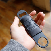 Black bottle opener held in a hand with a blurred background