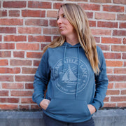 Woman wearing a blue hoodie with a logo against a brick wall
