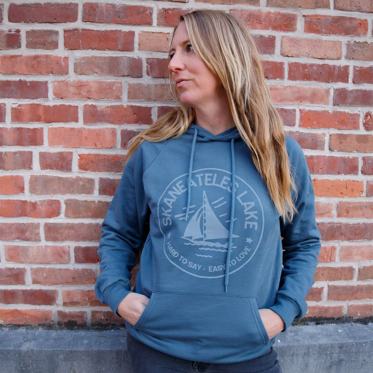 Woman wearing a blue hoodie with a logo against a brick wall