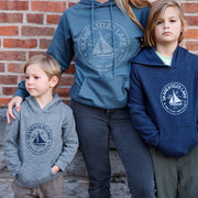 Three people wearing branded hoodies in front of a brick wall.