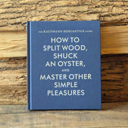 Blue book titled 'How to Split Wood, Shuck an Oyster, and Master Other Simple Pleasures' by Kaufmann Mercantile on a wooden background.