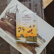 Book titled 'Bird Watching' on a wooden surface with bird illustrations.