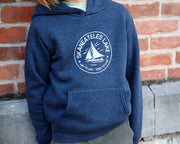 The Local Branch's navy blue hoodie with Skaneateles Hard to Say Easy to Love logo made in the USA pictured against a brick wall.
