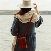 Model wearing cape, hat and leather satchel on the lake