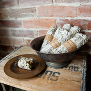 Bowl of smudge sticks on a wooden crate against a brick wall