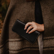 model holding The Local Branch's handmade leather pocketbook wallet in  black